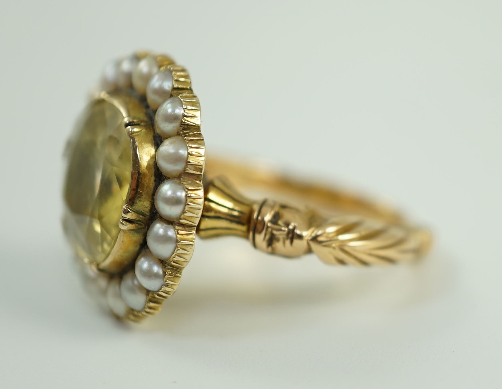 A 19th century style gold and round cut single stone yellow sapphire set dress ring, with split pearl set border